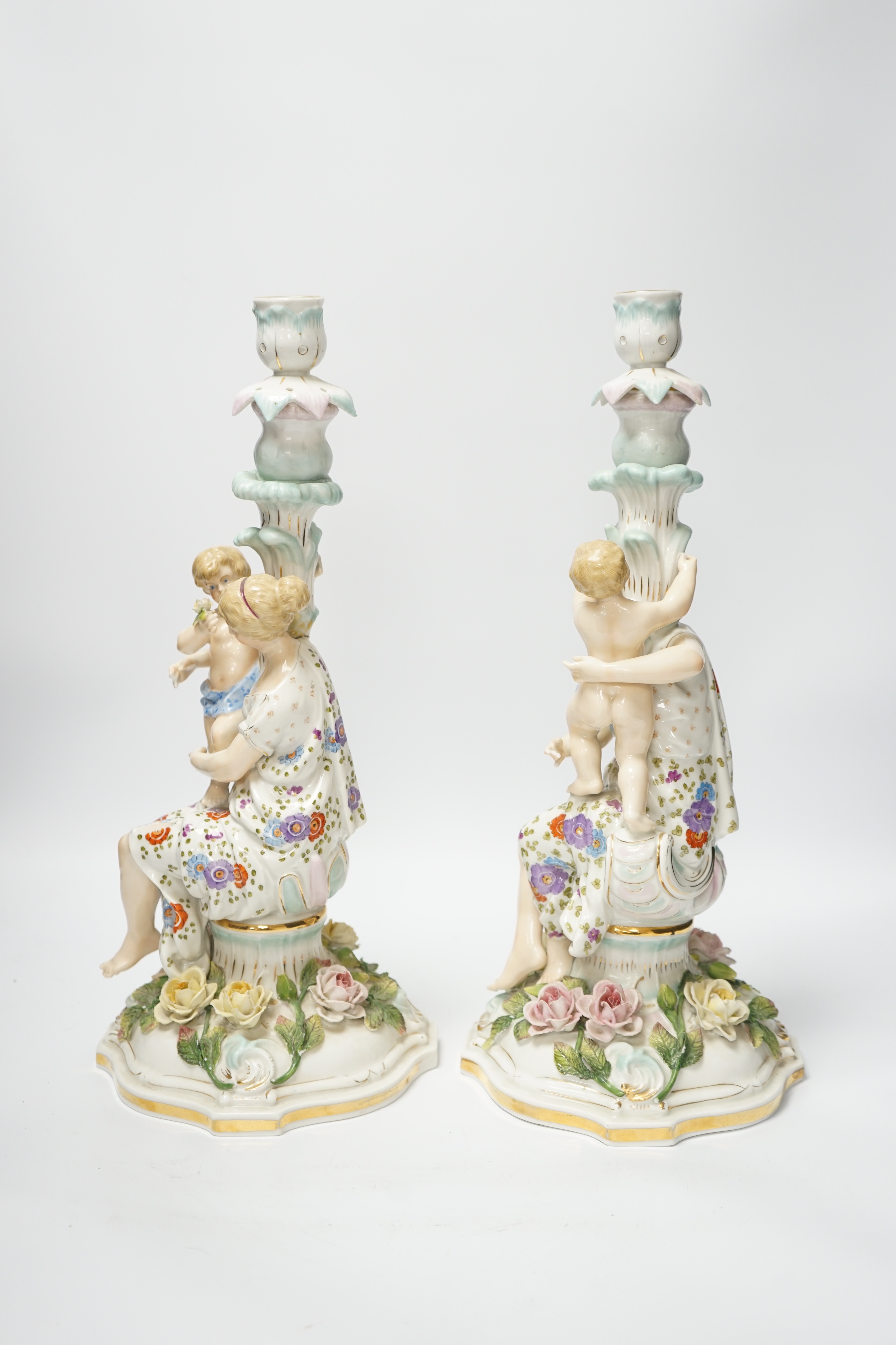 A pair of German floral encrusted porcelain candlesticks of a mother and child group, 38cm high